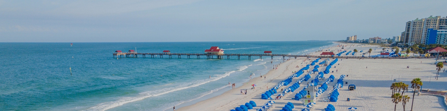 Rows of white-and-blue sunshades and beach chairs set up along a sandy beach