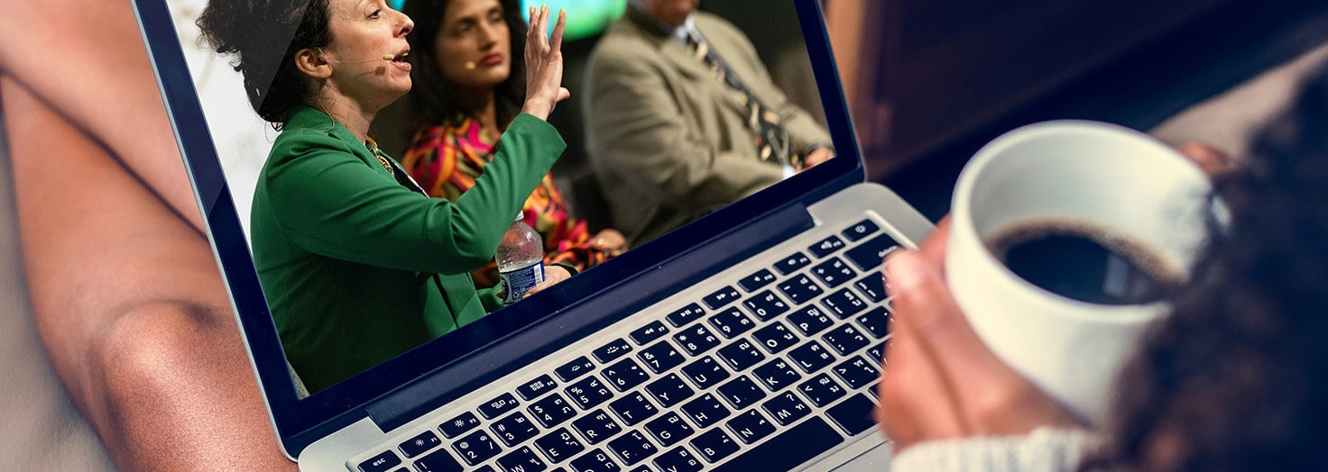 Person holding coffee watching online CME on laptop