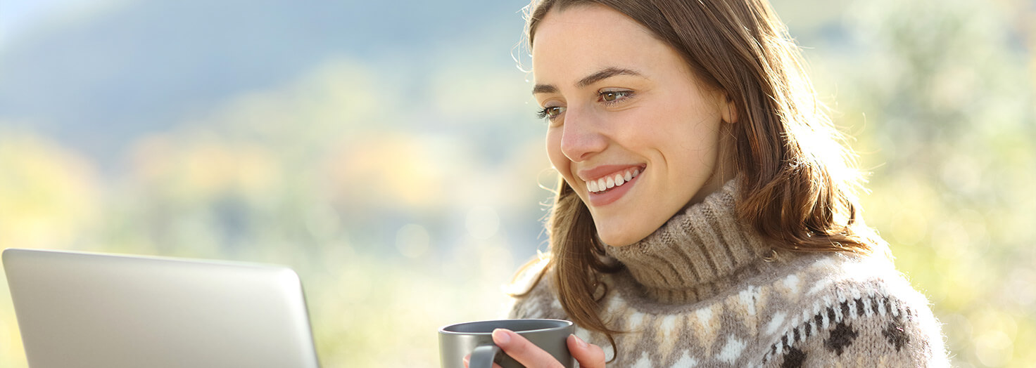 Person watching online CME on laptop with coffee cup in hand