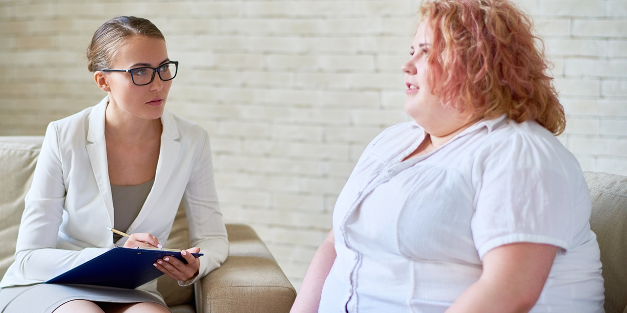 Doctor sitting with obese patient and taking notes