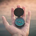 a hand holding a compass icon
