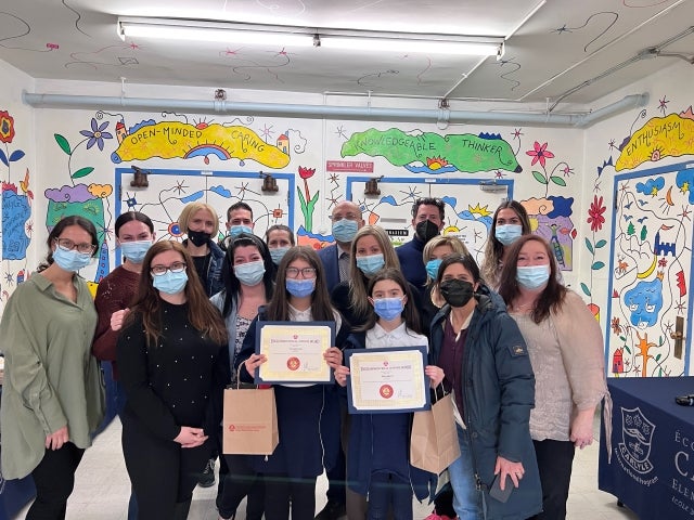Neva and Flora show their certificates in the company of their parents, staff, Chair Joe Ortona and Commissioner Ellie Israel.
