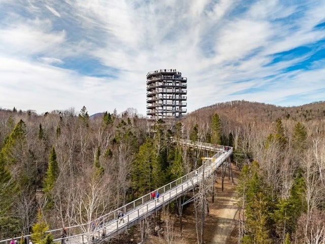  A photo of a walkway leading up to a large structure that shows the views of the Laurentian mountains at Sentier des cimes Laurentides