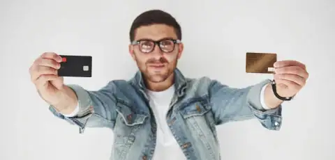 Persona caucásica con lentos sosteniendo comparando la diferencia entre tarjeta de crédito y débito