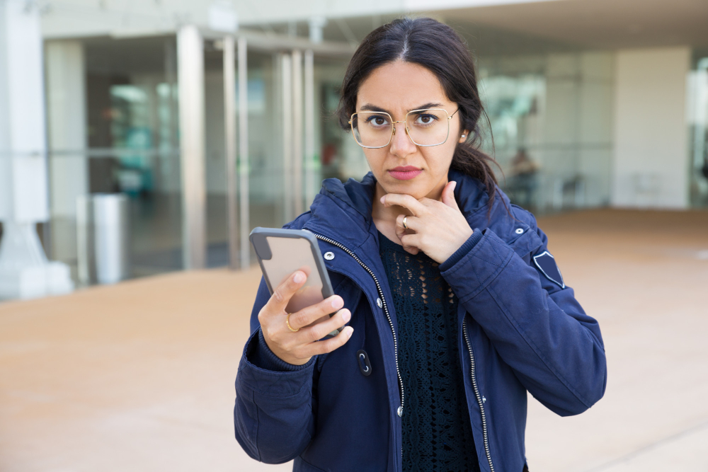 mujer con telefono en mano pensando