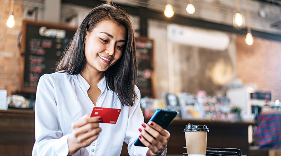 Mujer con celular agregando los datos de su tarjeta la banca m&oacute;vil