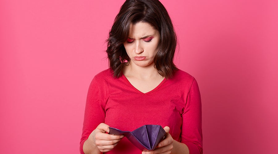 chica de rojo revisa su bolso con expresi&oacute;n facial triste al pensar en c&oacute;mo pagar sus deudas