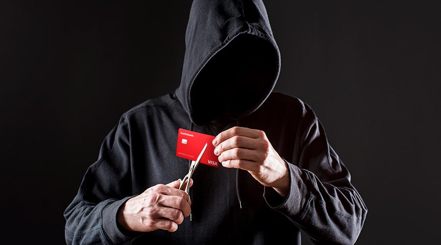 encapuchado a punto de cortar una tarjeta de d&eacute;bito