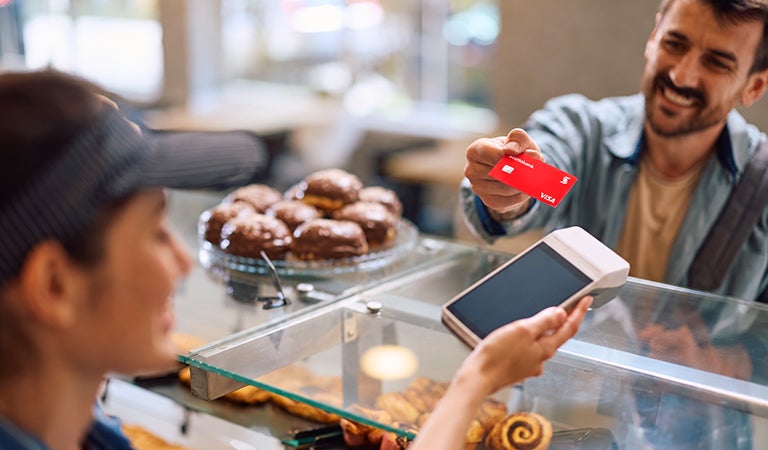 Hombre pagando con su tarjeta de cr&eacute;dito Scotiabank en el POS de una pasteler&iacute;a