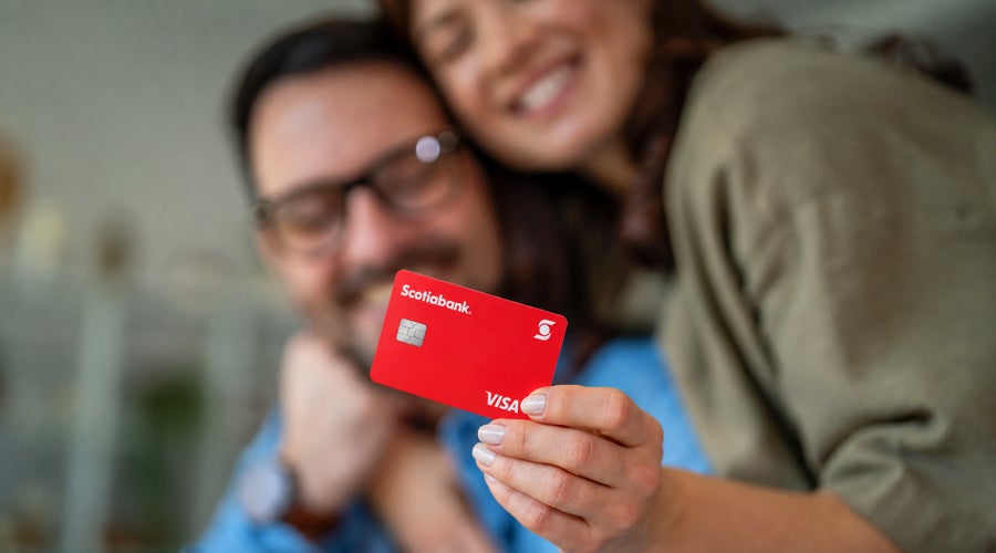 Pareja sonriente mostrando su tarjeta de cr&eacute;dito Scotiabank Visa