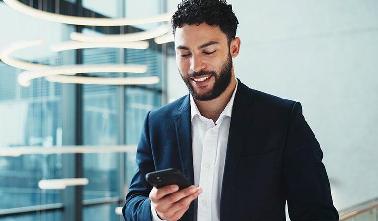 Trabajador sonriente usando su celular en la oficina de su empresa
