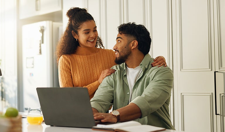 Pareja revisando opciones de pr&eacute;stamo en su laptop desde casa