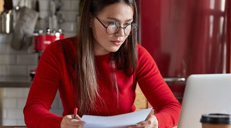 chica vestida de rojo revisando su laptop los gastos que tiene a nivel personal y evalúa su capacidad de endeudamiento