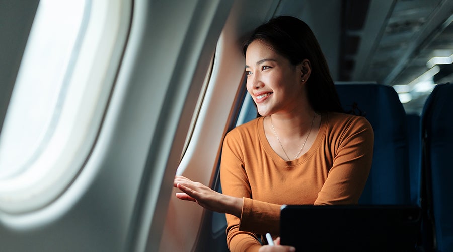 Mujer mirando por la ventana del avión durante el viaje que planeó con su depósito a plazo