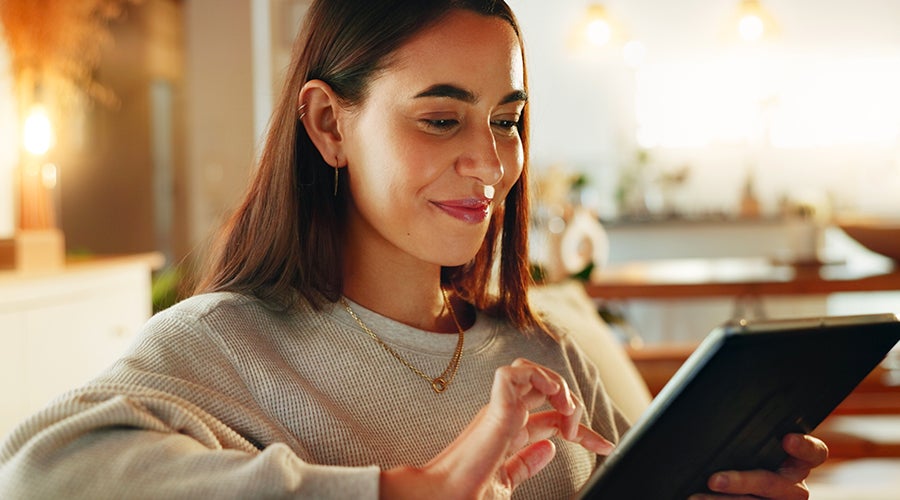Mujer sonriente comprando online desde su tablet en casa