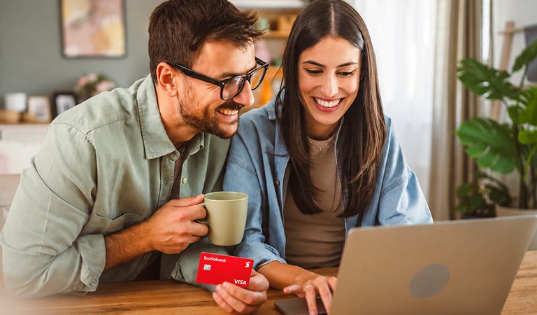 Pareja comprando online en su laptop con su tarjeta de crédito Scotiabank Visa