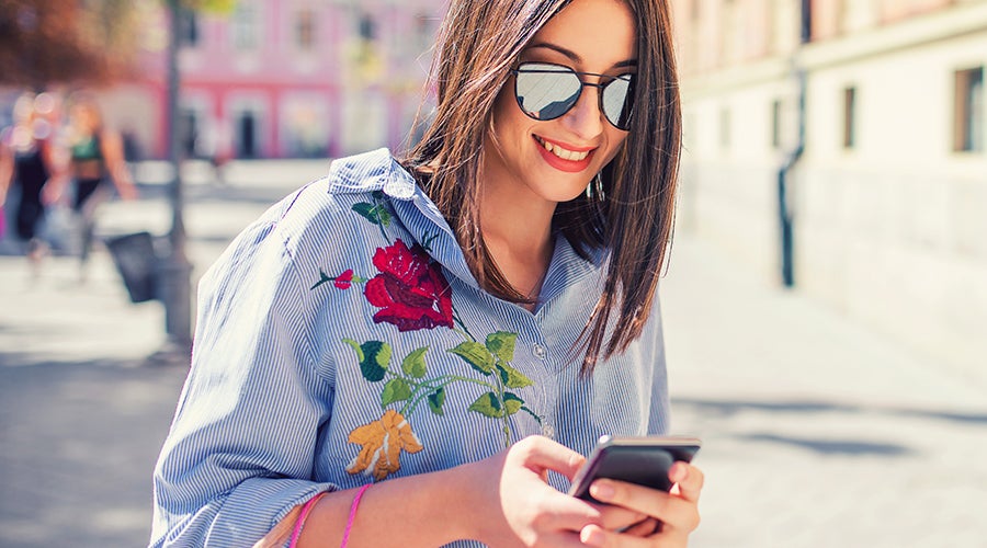 Mujer de viaje en el extranjero usando su celular en la calle