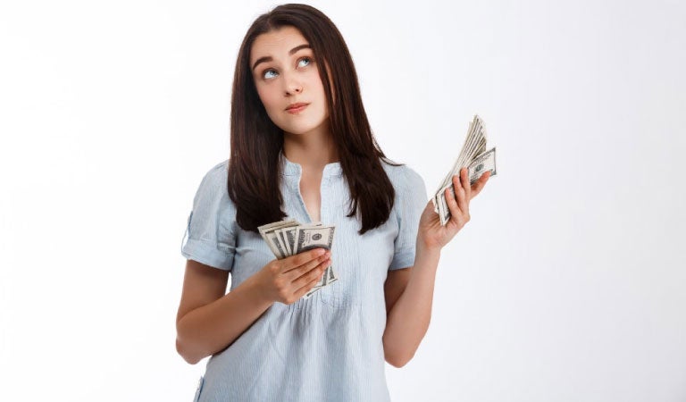 mujer con billetes en su manos pensando en ahorrar