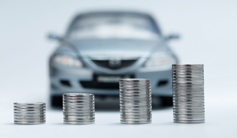 Monedas apiladas frente a un auto