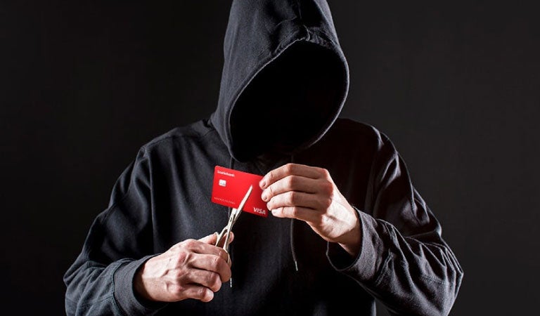 encapuchado a punto de cortar una tarjeta de débito
