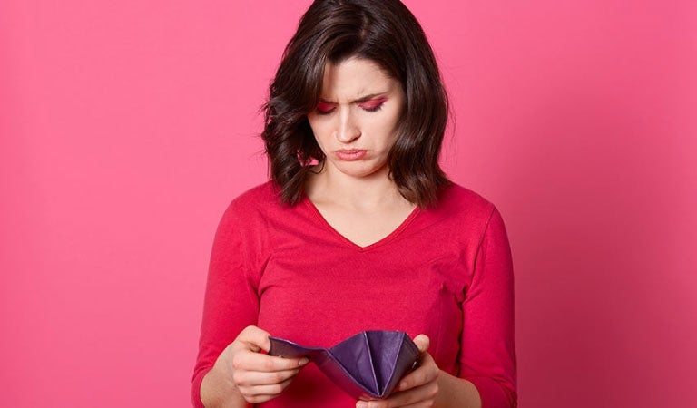 chica de rojo revisa su bolso con expresión facial triste al pensar en cómo pagar sus deudas
